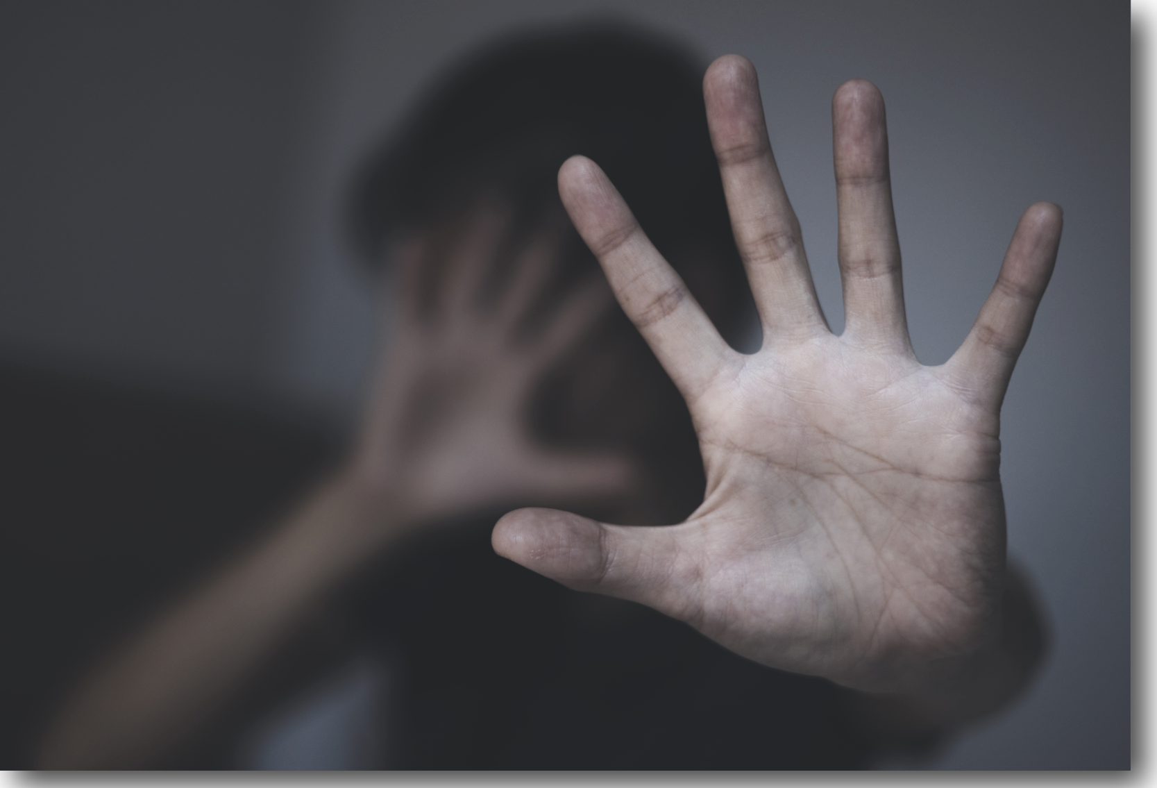 Pictured is a person holding up there hand to the camera as a sign of fear