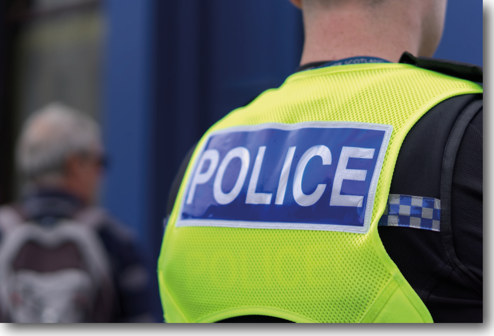 Pictured is a police officer in a reflective uniformed jacket with "Police" on the back